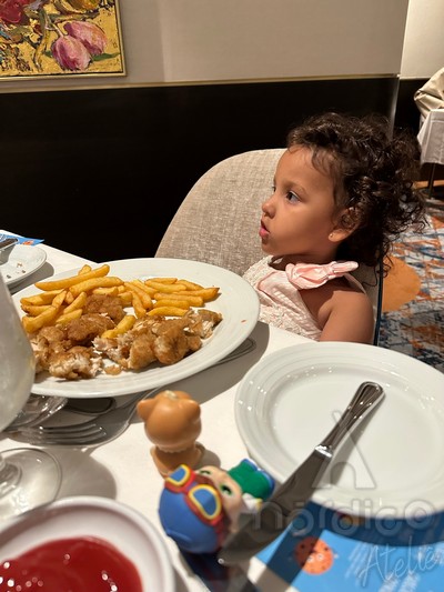 menina jantando um prato de frango com batata frita a bordo do odyssey of the seas