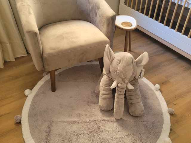 tapete infantil embaixo de uma poltrona de amamentação com uma pelúcia de elefante por cima