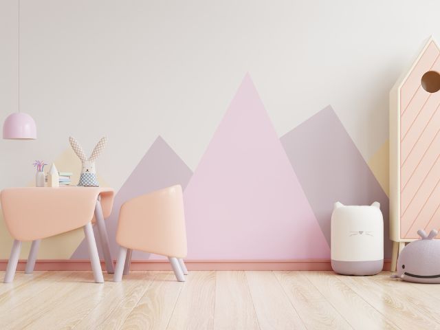 quarto infantl decorado em tons pasteis contendo uma mesa infantil