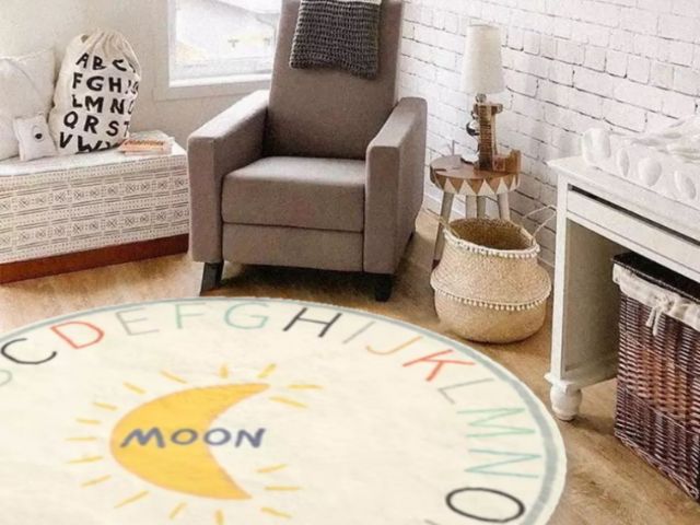 quarto infantil com cores neutras e tapete em tons vibrantes. o quarto possui poltrona, mesinha e cesto