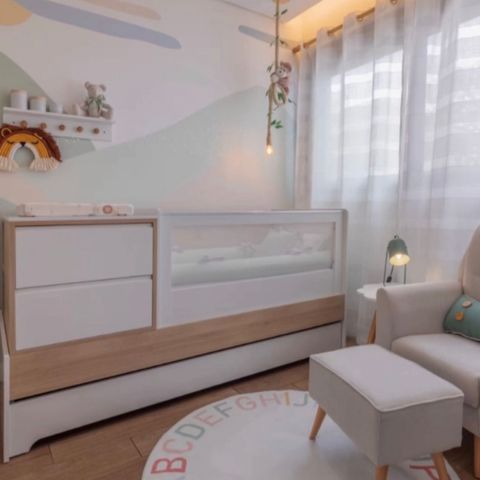 decoração de quarto infantil clean, com tapete infantil redondo, móveis com cores suaves e detalhes em madeira, adesivo de parede simulando montanhas